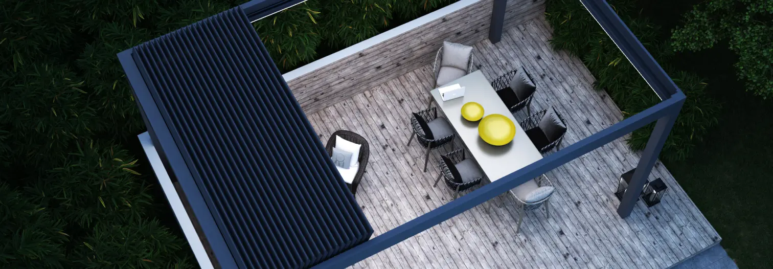 Aerial view of a modern outdoor patio with a wooden deck. Features a dining table set, green cushions, and overhead pergola, surrounded by lush trees