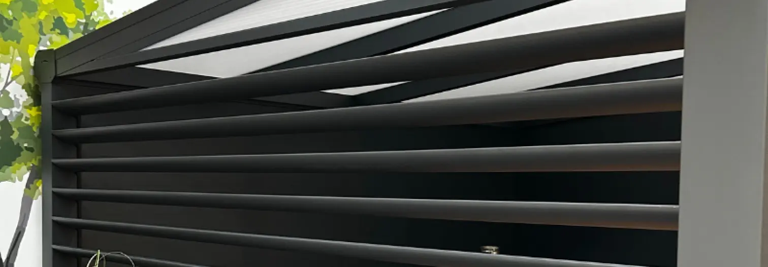 Modern outdoor pergola with sleek, horizontal black slats for shade. A tree and light gray wall are visible, conveying a minimalist, contemporary style