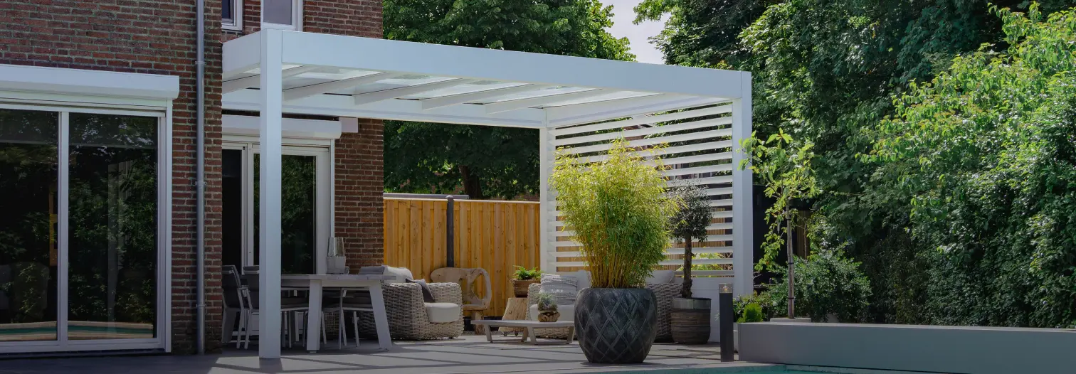 Modern patio with a wooden pergola, outdoor seating, and potted plants. Surrounded by lush greenery, it exudes a tranquil, inviting ambiance